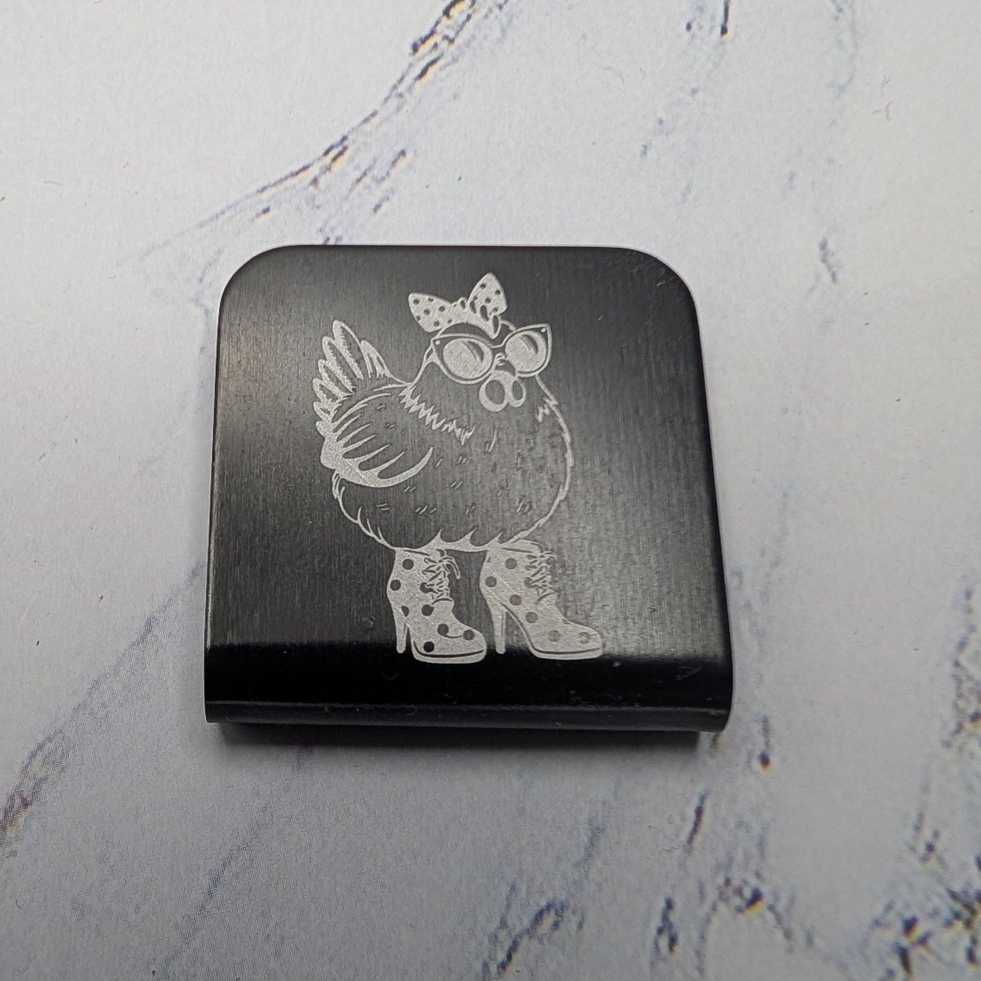 Black hat clip with a chicken character on a marble surface