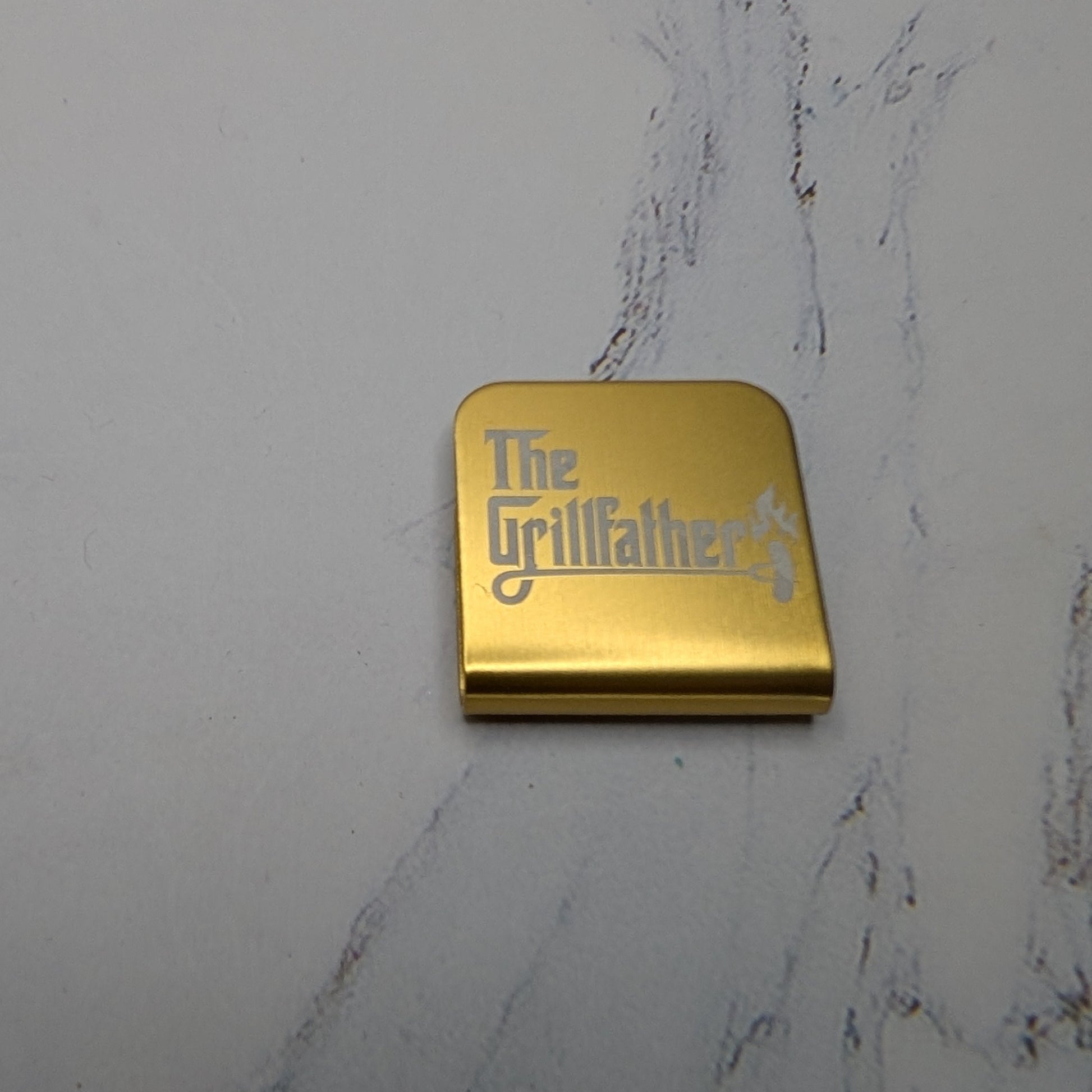 Gold hat clip with the words 'The Grillfather'